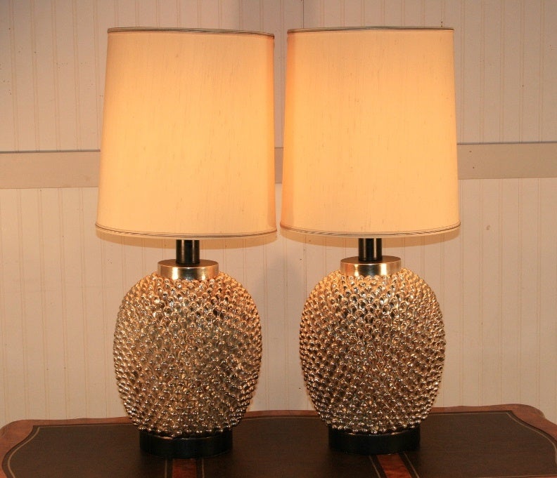 Substantial pair of vintage glistening Hollywood Regency ceramic or pottery designer lamps with high style form having a gold or silver polychrome painted finish. I say gold or silver because the color looks gold or silver in certain lights. These