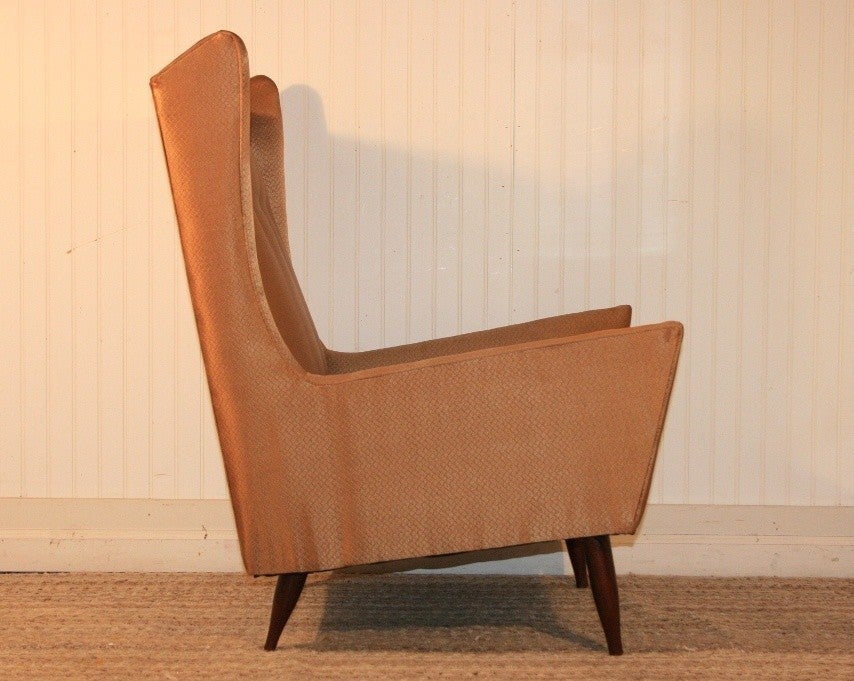 Stunning 1950's Mid Century Modern Sculptural Wingback Lounge Chair with a great art deco feel. Item features a unique winged back, solid mahogany tapered legs, angled frame, button tufted back, and very nice original light brown satin-like fabric.