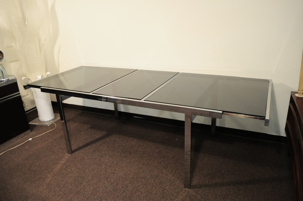 Vintage Mid Century Modern Very Clean Polished Chrome Extension Dining Table with smoked glass top. This is believed to be designed by Milo Baughman for Thayer Coggin. This high quality table is  heavy and and very well constructed with a polished