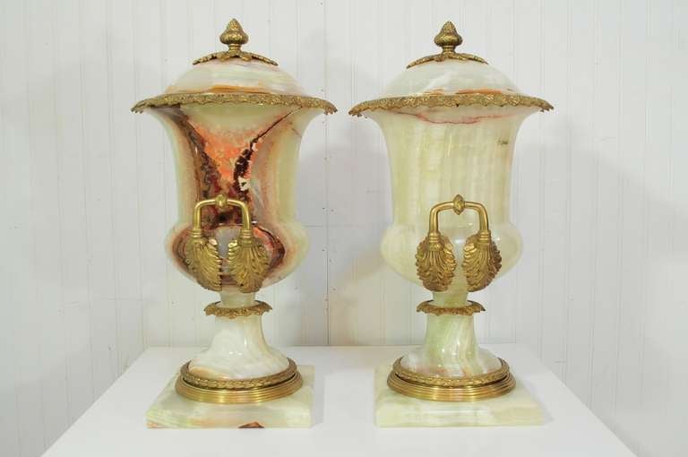 Large pair of 20th century urn form lidded cassolettes in onyx and bronze in the French Louis XVI taste (The lids are affixed and not removable). The pair features the most dramatic veins throughout the polished onyx stone with attractive cast
