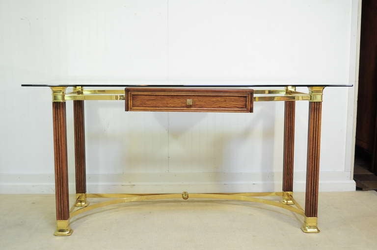 Very Unique Vintage Italian Hollywood Regency Brass, Glass, and Oak Wood Desk. This item was made in Italy and features a large glass top with rounded corners, brass stretcher base and accents, as well as one dovetailed floating form drawer with