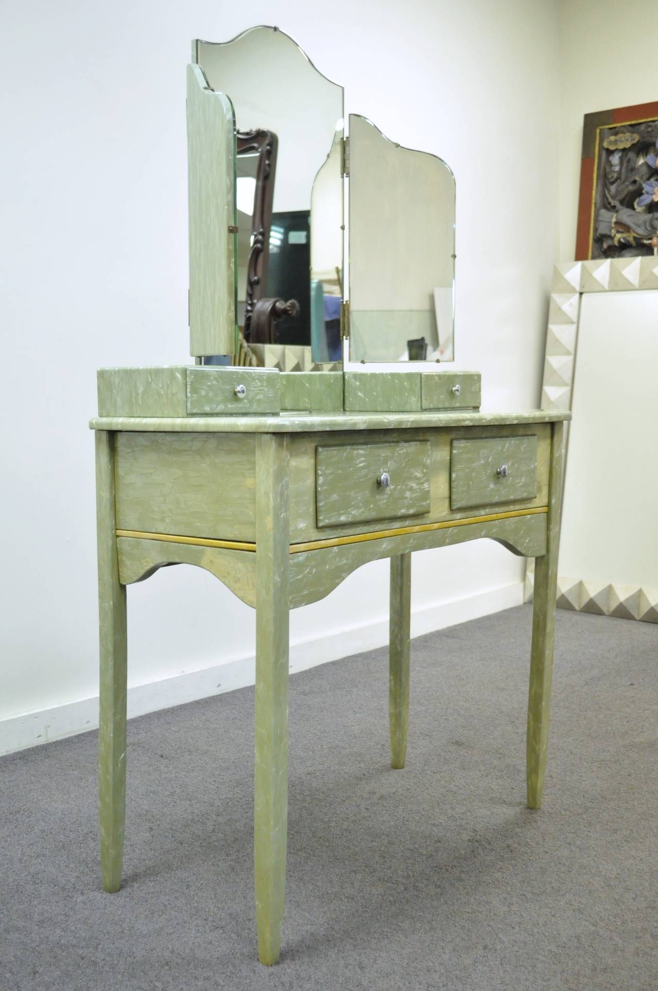 Extremely unique and interesting vanity with matching tri-fold mirror and vanity bench comprised of real celluloid over wood. This rare set has a very striking appearance, thanks to the iridescent tones of the light green celluloid, and the simple