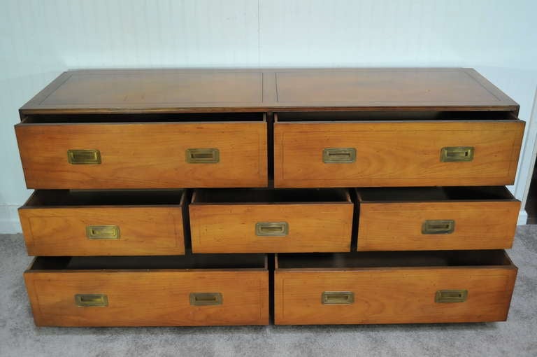 Beautiful Vintage Baker Furniture Co. Campaign Style 7 Drawer Long Dresser with Brass Inset Pulls. Item features seven dovetailed drawers with solid brass pulls, bun feet, and original lightly distressed/antiqued Baker finish.