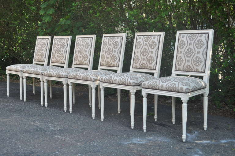 Elegant set of Eight 20th Century Cream Distress Finished Dining Chairs in The French Louis XVI Taste. This classy set of chairs features six side chairs, two armchairs with reeded and tapered legs, rosette carvings, nail head trim, fully