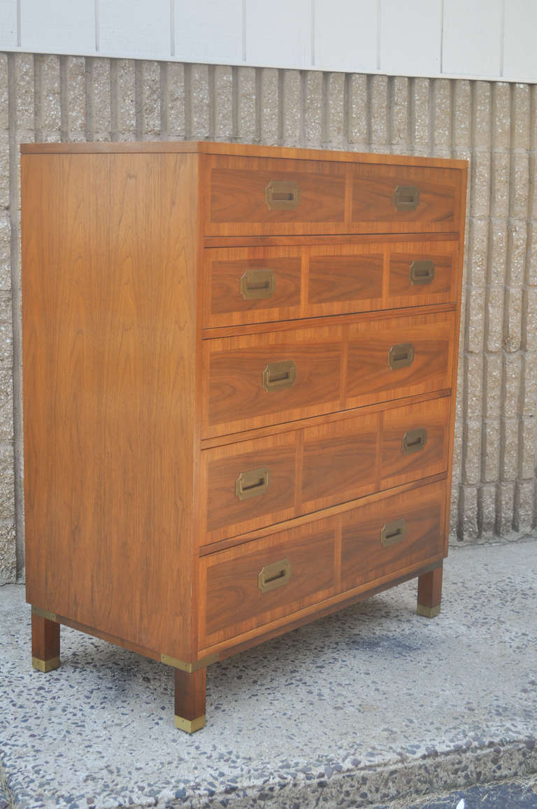 Vintage Mid Century Modern Milling Road Tall Dresser by Baker. The dresser features a very nice Hollywood Regency / campaign style design with striking, figured wood grain, 5 dovetailed banded front drawers, banded top, and lovely brass accents
