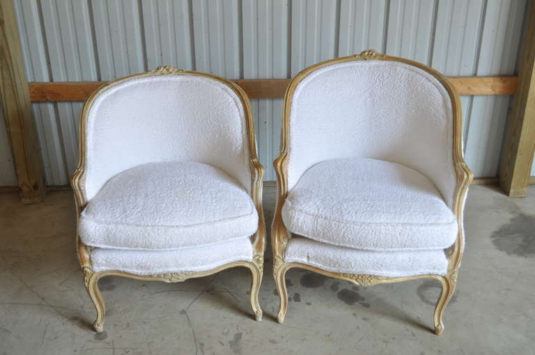 Compatible Pair of Beautiful Vintage His & Hers French Louis XV Style Bergere armchairs. The chairs feature floral accents at the top rail and legs, scroll work carvings at the arms, carved cabriole legs, and an overall nicely distressed white