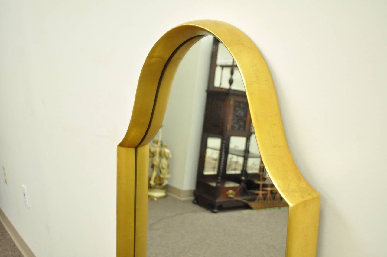 Very striking Hollywood Regency deep frame wall mirror with a very appealing distressed gold gilt finish over the carved wood frame. The piece has a great overall shape with clean modernist lines.