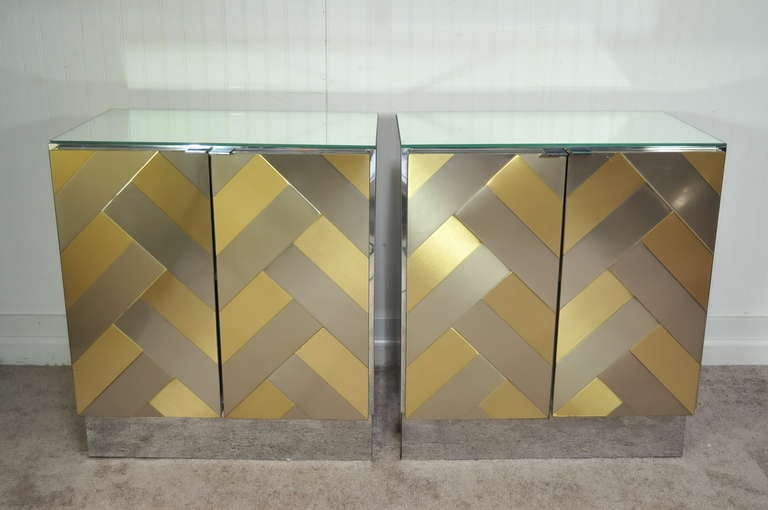 Very unique Pair of Mid Century Modern / Hollywood Regency Nightstands or End Tables by Ello in the Paul Evans Style. The pair features mirrored glass tops with brass and steel/chrome chevron pattered door fronts and mirror paneled sides and bases