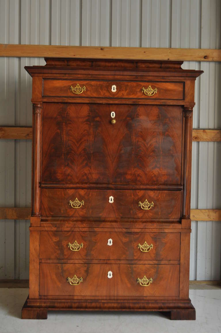 Antique French Empire Period two Part Flame Mahogany Drop Front Abattant. Item features beautiful tapered capitol, brass hardware, mother of pearl keyhole covers, inlaid interior with beautiful outdoor and courting scenes, and quality dovetailed