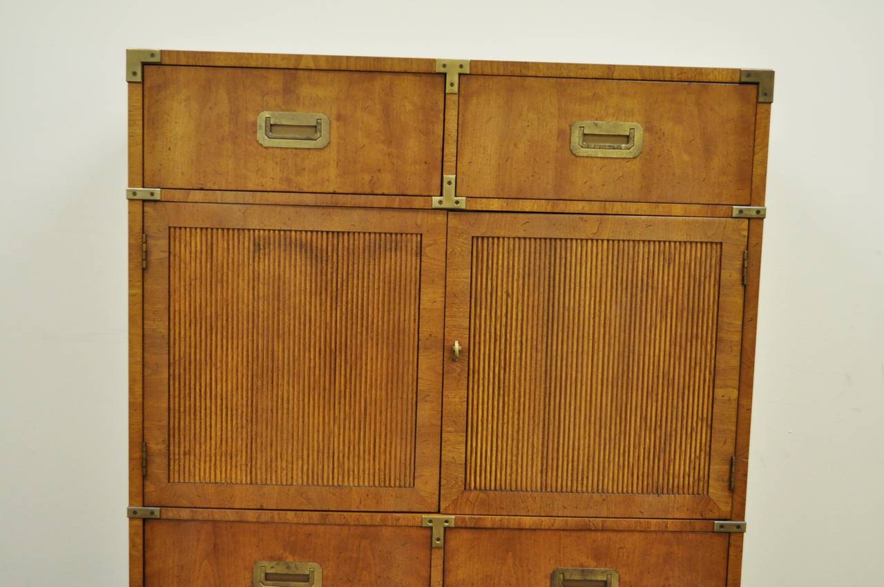 Quality vintage Campaign style chest of drawers by Henredon. Item features a walnut case with beautiful grain, inset antiqued brass hardware, six dovetail constructed exterior drawers, two swing doors with inner compartments, clean lines, and
