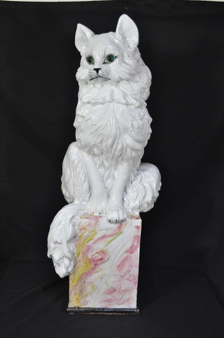 We like to refer to this stunning Vintage Terra Cotta Glazed Sculpture as Terra Cat, Ta. This super fun whimsical piece features a tall refined kitty cat perched upon a pink glaze decorated pedestal. The sculpture features green glazed eyes, finely