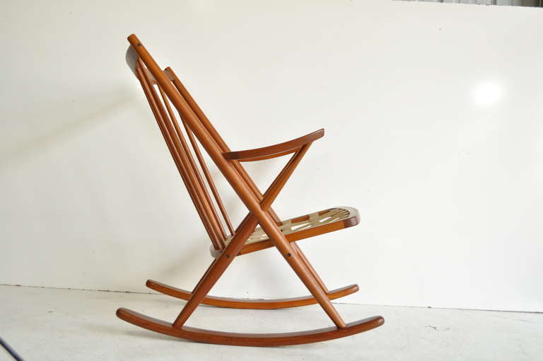 Stunning Vintage Mid Century Danish Modern Solid Teak Rocking Chair designed by Frank Reenskaug for Bramin. The chair features clean modernist lines, beautifully defined teak wood grain, curved back, and great form.