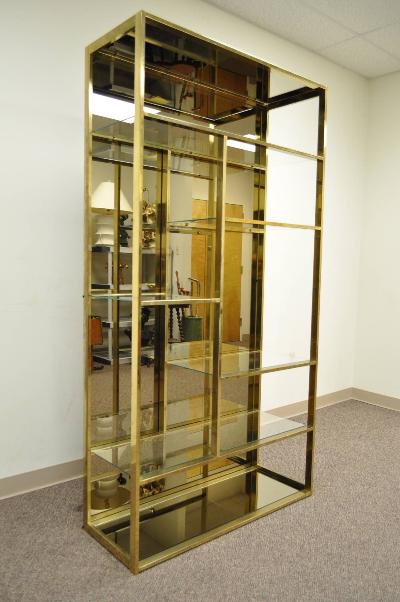 Stately Mid-Century Modern Etagere with an attractive burnished brass-plated finish to the metal frame and a amber mirrored back attributed to Milo Baughman. This item features a amber colored mirrored glass back as well as amber mirrors on the very