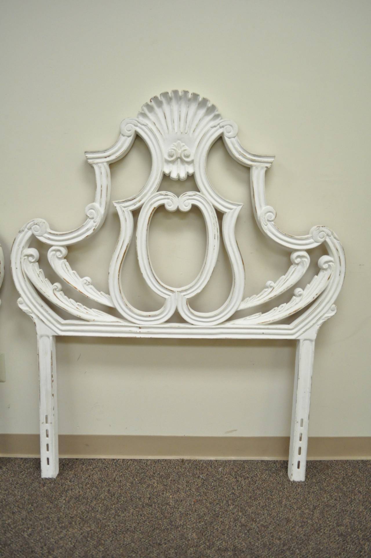 Very unique pair of wonderfully cast metal, shell form, single bed headboards in the French Rococo / Hollywood Regency style. This vintage pair features scrolling forms with shell designed pediments. Headboards are finished in an antiqued white