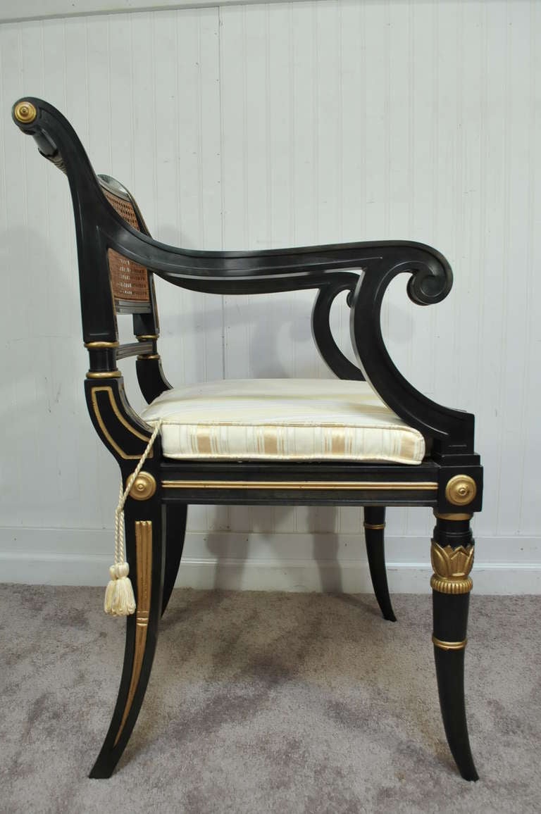 Remarkable Baker Stately Homes Collection Carved, Gilded, and Painted Regency Open Arm Chair with Cane Back and Upholstered Seat. Item still has the original Baker hang tag and metal label on the underside.