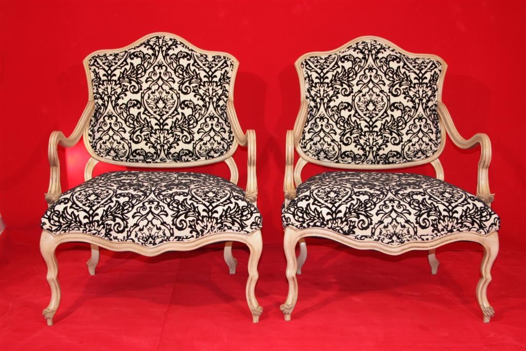Pair of vintage Italian Hollywood Regency boudoir armchairs having low wavy forms and fine carvings throughout. Believed to date back to the 1960s. The pair features newer black and white raised pattered Damask print fabric which compliments the