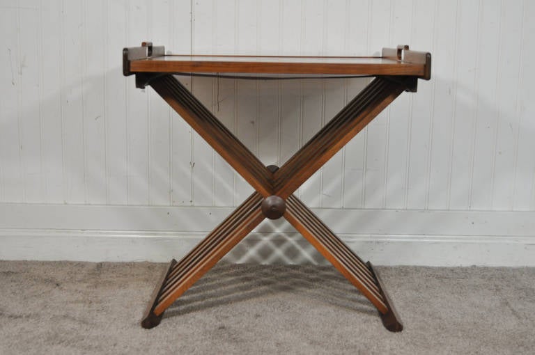 Beautiful Vintage Campaign Style Walnut Folding Tray or Serving Table designed by Stewart MacDougall for Drexel. This table features a removable serving tray top, sculpted wood finials, and great modernist form.