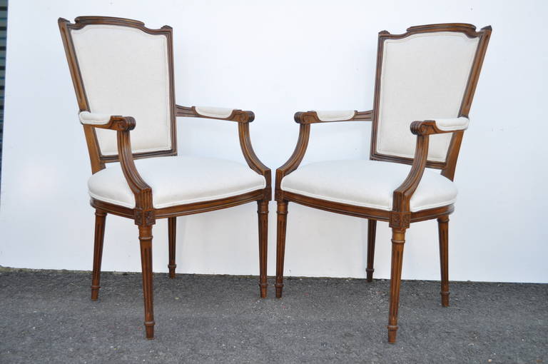 Classy set of six vintage Louis XVI style newly upholstered carved walnut dining room chairs consisting of two armchairs and four side chairs. The set features reeded and tapered legs, shaped backs and new foam, webbing and fabric in an oatmeal