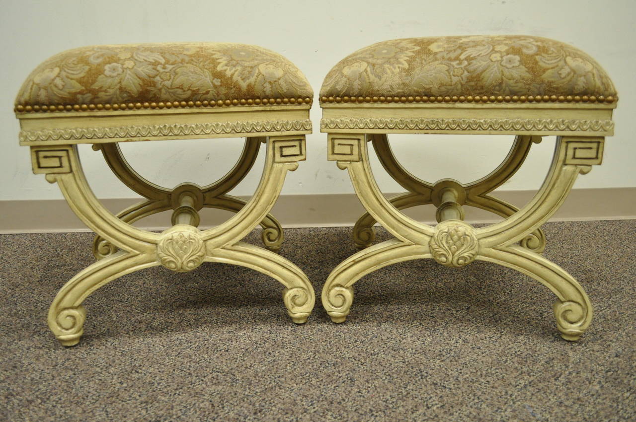 Quality pair of 20th Century Carved and Paint Decorated Curule Benches in the French Neoclassical taste. The pair features solid wood carved frames, nail head trim, upholstered seats, and elegant neoclassical form.