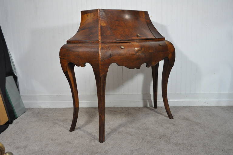 Very unique vintage Italian burled olive wood console or commode with very elegant silhouette. Item features a thick, solid wood, flip top,shapely saber legs, two small drawers, and a very shapely, bombe form. This console would work wonderful in an