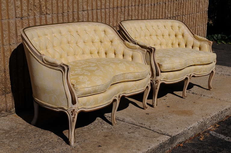 Remarkable pair of early to mid 20th Century French Louis XV Style Canapes with yellow tufted fabric and distressed cream / dark antiqued gold/green painted finish to the frames. The settees feature 5 carved cabriole legs, nicely tufted upholstery