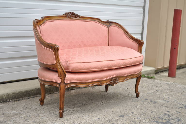 Beautiful vintage French Louis XV / Country style carved walnut and pink upholstered settee. Item features four shapely cabriole legs, solid wood frame, carved pediment at the upper and lower rail, curved and carved arms, and great overall ovoid