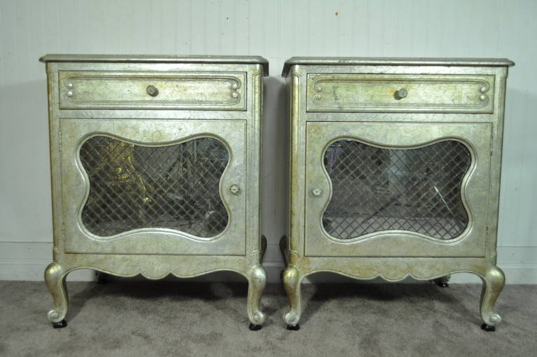 Stunning Pair of Custom Vintage Hollywood Regency, French Louis XV Style Nightstands in the Manner of Maison Jansen. The pair features original silver and gold leaf finish, mirrored door fronts, heavy solid wood construction, sturdy dovetailed