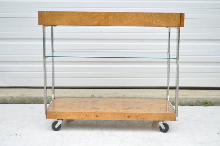Vintage Lane Burl Wood, Flat Bar Chrome, and Glass Bar Cart by Lane in the Milo Baughman style. Item features two pull out surfaces, seamless flat bar chrome supports, rolling casters, center glass shelf, and beautiful figured wood grain throughout.