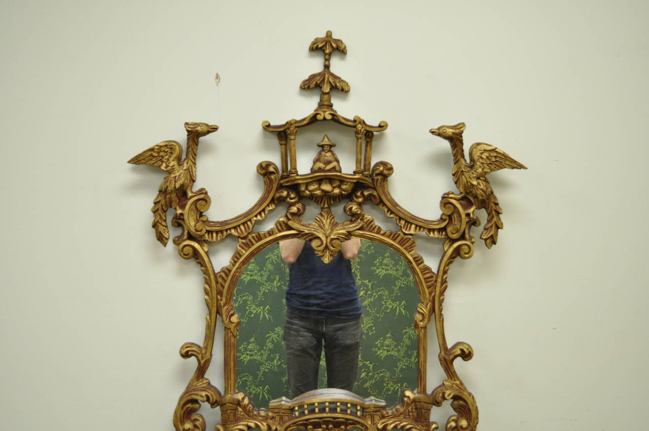 Stately vintage carved wood wall mirror in the Chinese Chippendale / Chinoiserie style. This beautiful item features a nicely carved pagoda form frame with a seated gentleman under the pagoda, two carved ho ho birds, and other floral acanthus and