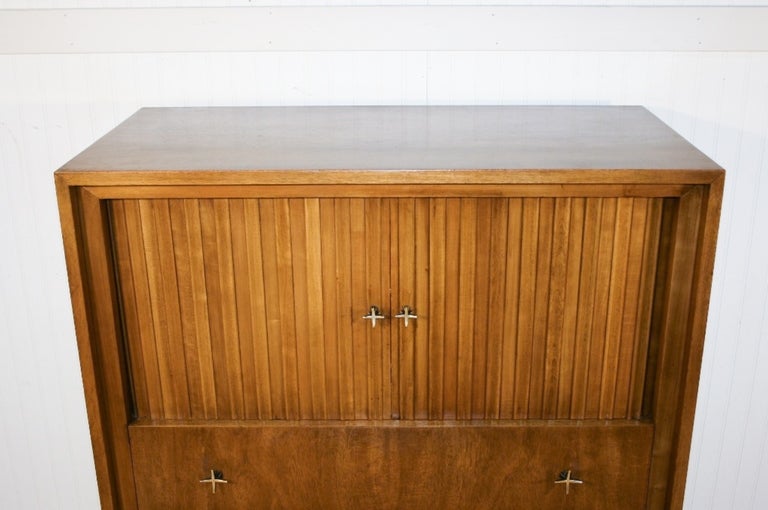 Vintage Mid-Century American Modern mahogany chest by John Widdicomb with tambour doors and solid brass star hardware. This dresser features shaped feet, three exterior dovetail constructed drawers, one small interior drawer and stunning