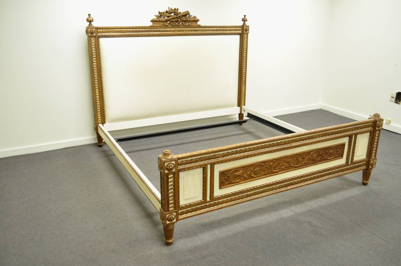 Stunning king-size French Louis XVI style hand-carved giltwood bed by Ralph Lauren Home. This beautiful bed features an ornately carved, gold gilt decorated, footboard, headboard, and rails. Item features reeded and tapered legs, plume carved