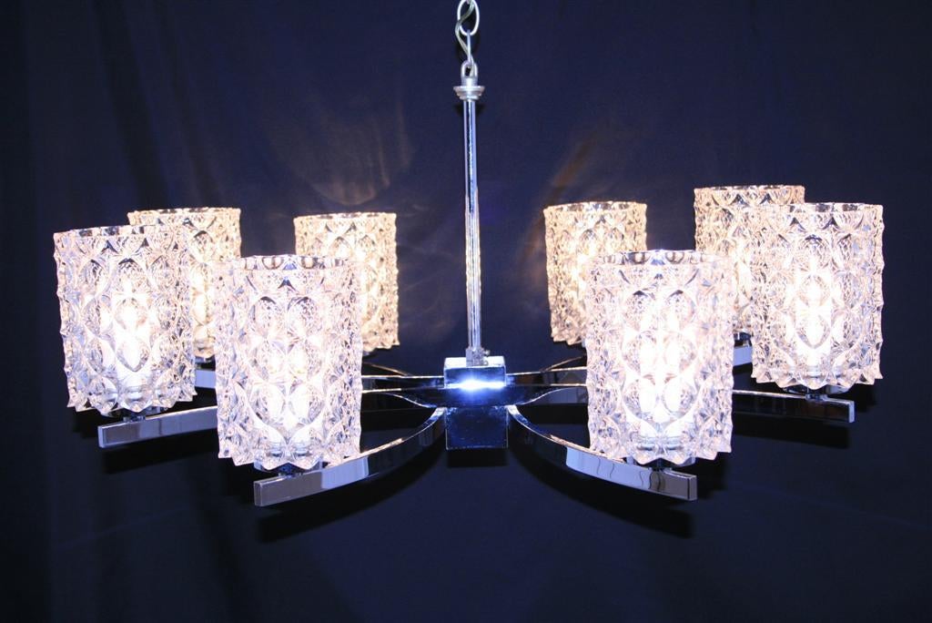 High quality eight-light Mid-Century Modern polished chrome and clear glass chandelier by Kaiser Leuchten. This vintage fixture features a sleek sculptural chrome frame and eight crystal shades in the thousand eyes pattern. The modernist form and