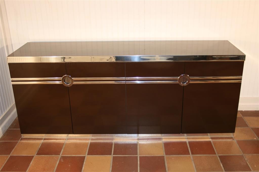 Wonderful 1970's-80's Mid Century Modern Chocolate Brown Lacquered 4 Door Cabinet by Pierre Cardin with Mirrored Chrome Trim. Item has a beautiful Art Deco Feel with 2 Hidden Drawers and great Modernist Form. 

Keyword Search: Credenza, Sideboard,