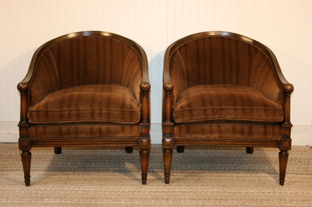 Remarkable Pair of Vintage Neoclassical Style Barrel Back Armchairs from the 1950's. These wonderful chairs feature ball form armrests, nailhead trim, tapered legs, sumptuous down filled cushions, upholstered backs, and fabulous stylish form. The