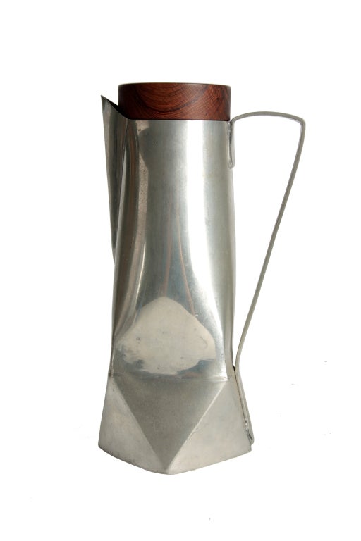 A very nicely executed pewter pitcher in the modernist style. 
Hand bent, faceted planes ending in a solid rosewood top stopper.