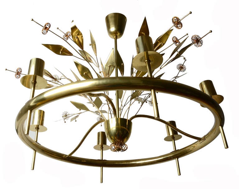 A spectacular example of a custo chandelier by Finnish lighting Master Paavo Tynell for Taito Oy.

This piece is hand made of solid brass.  Trademark leaves, berries and blossoms explode from the centre bowl like fireworks. 
Three delicately