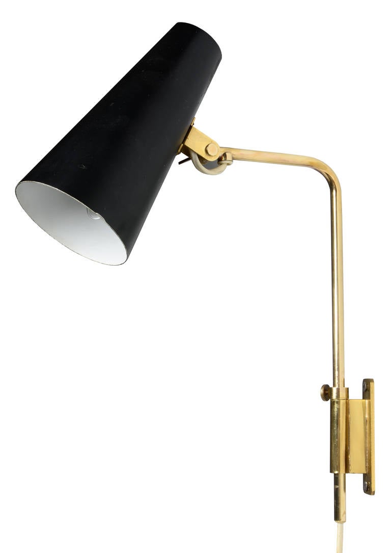 A pair of solid brass adjustable wall lamps with black painted shades. Designed by Paavo Tynell for Taito Oy; a beautiful and elegant design.