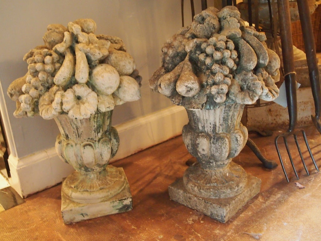 Pair of weathered cast stone fruited urns with lovely patina. would make wonderful finials atop stone columns
