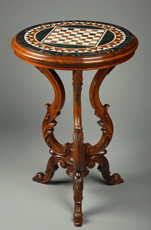 A 19th century Italian pedestal in sculpted wow with scrolls and an inlaid marble top with a chess game.