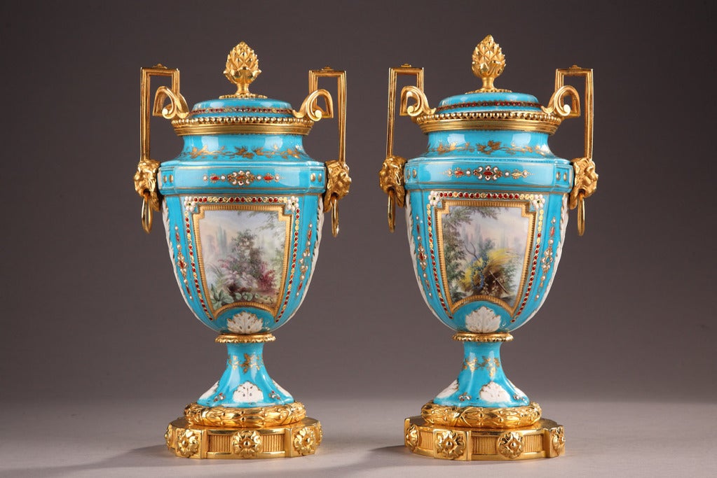 Fine pair of English porcelain vases and gilt bronze mounts resting on a circular base with fine fluting and floral patterns. The two vases are ornamented with polychrome cartouches representing pastoral scenes in the style of the XVIIIth century.