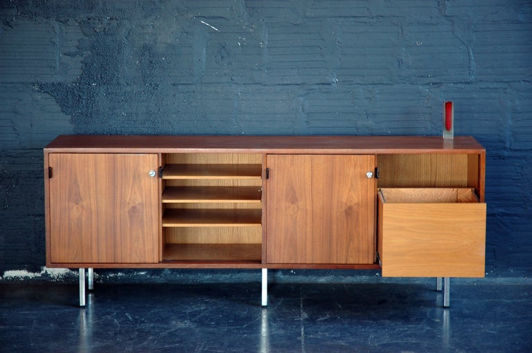 An incredible refinished credenza by Florence Knoll.  Sliding doors with leather pull tabs, two roll-out file drawers and two compartments with adjustable-height shelving.  Polished metal legs.