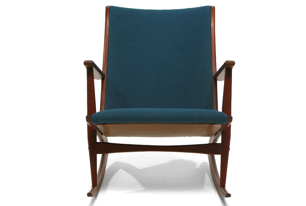 Made in Denmark by Kubus
 
Teak-frame rocking chair produced in 1958 by Kubus in Denmark.  Especially beautiful in profile, where the curving rocker and tapering seat back contrast with the linear armrest and support.  This piece is in excellent