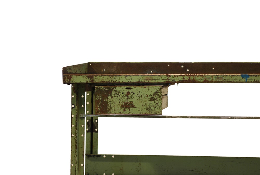 A heavy, solid industrial workbench from Lyon. Years of wear and hard use have worn the steel to a beautiful patina. Weathered, raw steel shows through the top layer of paint.