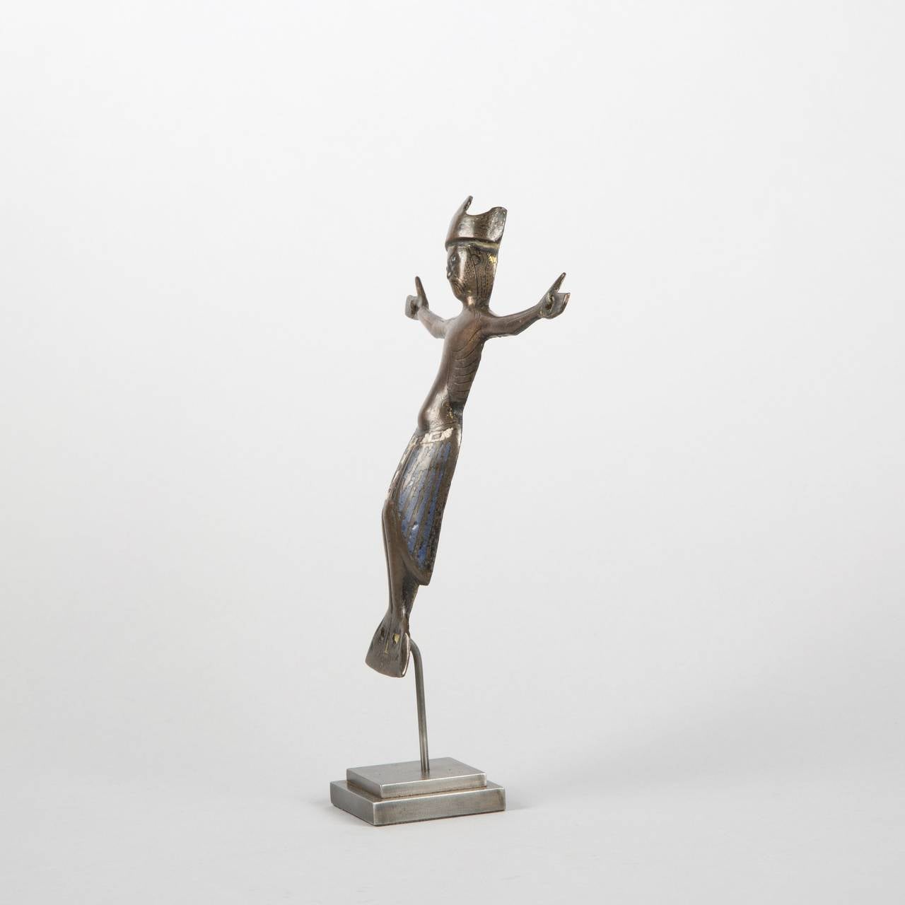 Engraved, champlevé-enameled and enameled copper wall Christ with gilt remnants and glass eyes. Head encircled with crown of stylized fleurons, swollen abdomen, long perizonium falling on sides, bent legs, parallel feet atop a