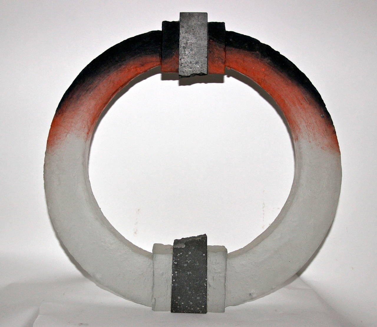 Colin Reid (1953), Sculpture, 
Glass and lava stone, 
Ring shape with decoration in orange and black tones,
circa 1980, England.

Measures: Height: 52 cm, diameter: 51 cm, depth: 9 cm.

Colin Reid has achieved worldwide acclaim for his mastery of