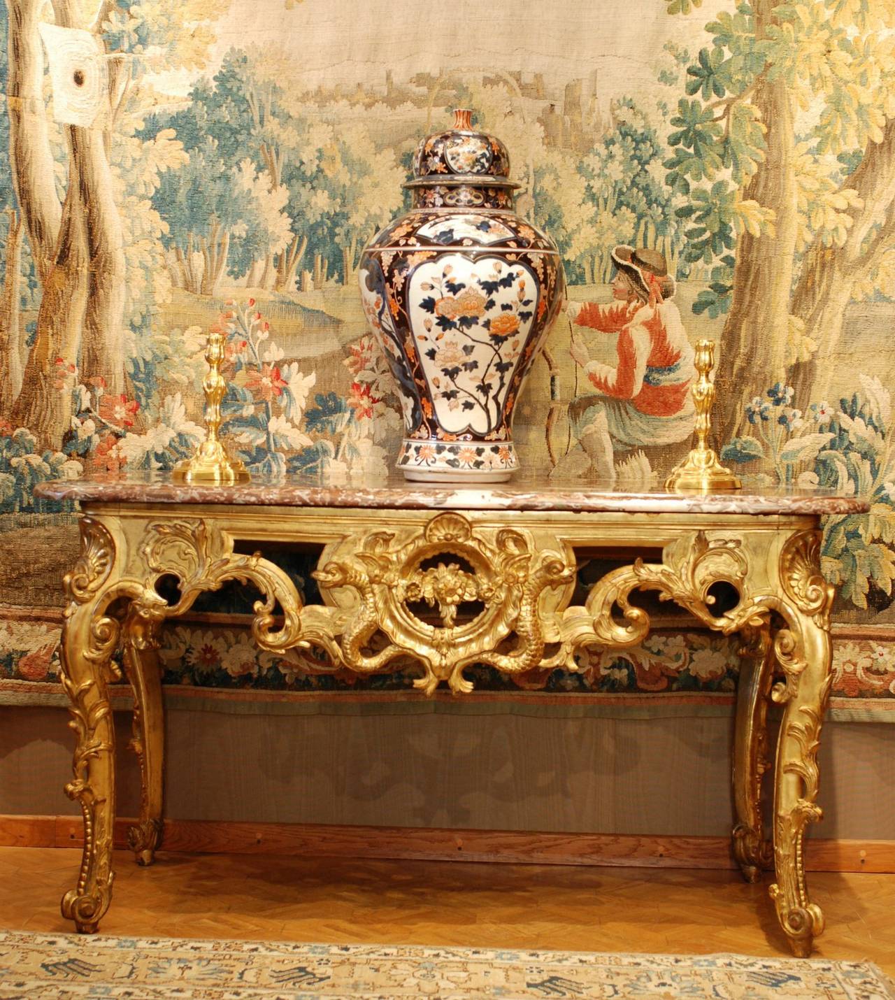A giltwood console table, surmounted by a red moulded marble top with pierced apron on four cabriole legs with scroll feet.