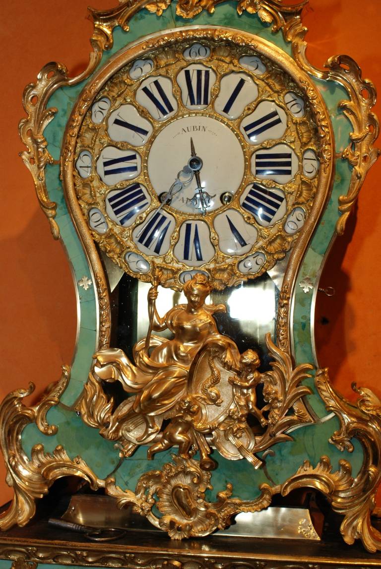 The eleven inch repoussé-decorated brass dial, all within a ring of 24 enamel cartouches with Roman hours and Arabical minutes, centered by a round enamel signed Aubin à Paris, the case with scrolls and foliage surmounted by a dragon, all raised on