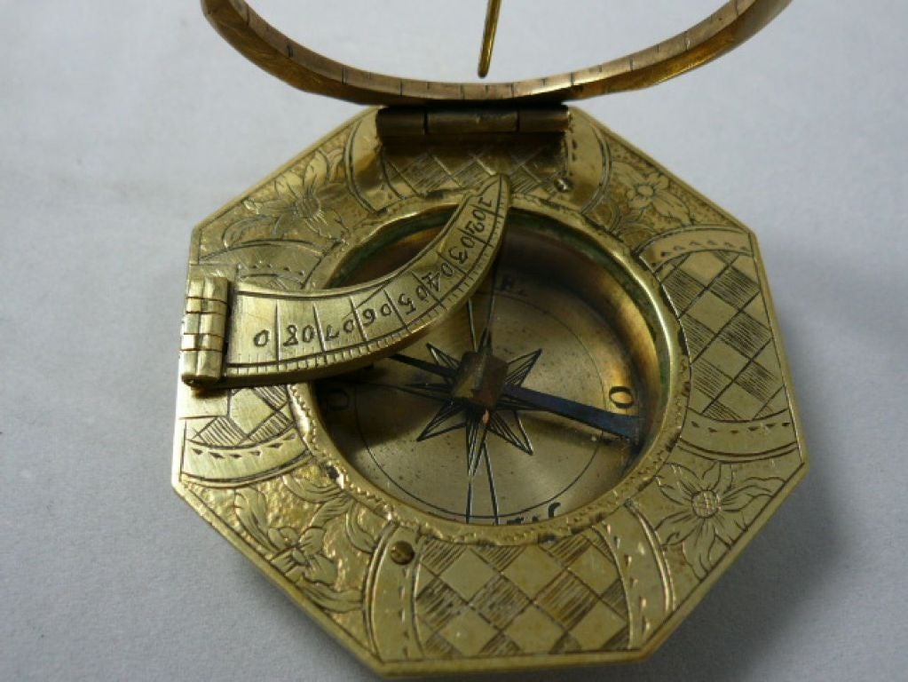 Horizontal  octagonal sundial plate decorated with geometric motifs and the flowers.
Folding circle on which are engraved the hours.
The back of the compass are engraved the latitude of several cities and the manufacturer's name 