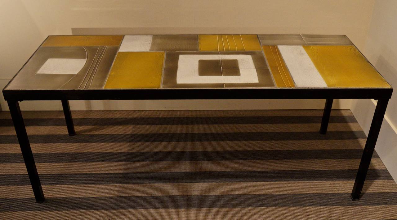 A rectangular coffee table consisted with a glazed lava tiles table top in shades of gray, amber and gold tones.
Signed R. Capron on one tile. 
Vallauris.