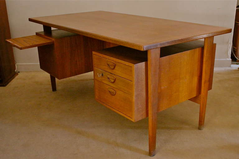 Large teak wood Scandinavian desk with four front drawers and a pull-out shelf. Three opened trunks on the back. Good condition.